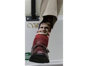 Former President George H.W. Bush wears socks with his image as he sits in a cart on the sidelines before an NFL football game between the New England Patriots and Houston Texans on Dec. 1, 2013, in Houston.