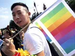 FILE - In this Oct. 27, 2018 file photo, a participant carries the rainbow flag during the annual gay and lesbian parade, organized by Taiwan LGBT Pride, in Taipei, Taiwan. This time of year can be tough for LGBTQ children and teens when it comes to gatherings. And advocates believe there's even more at stake when shifts in identity, new names and pronouns, unsupportive relatives and a general lack of knowledge about related gender issues are in play, particularly for the first time.