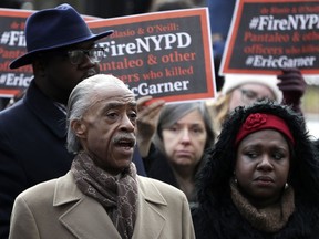 Rev. Al Sharpton, left, stands with activists while speaking during a news conference outside of New York Police headquarters, Thursday, Dec. 6, 2018, in New York.  Daniel Pantaleo, a New York City police officer accused in the 2014 chokehold death of Eric Garner, an unarmed black man, will face a disciplinary trial in May.