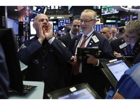 In this Thursday, Nov. 29, 2018, photo, specialist John O'Hara, left, works with traders at his post on the floor of the New York Stock Exchange. The new cease-fire in the trade dispute between the U.S. and China should boost rattled financial markets, at least likely through year's end. But the stock market's wild gyrations of recent months likely will persist as the two countries strain to reach a permanent accord in the next three months, some experts say.