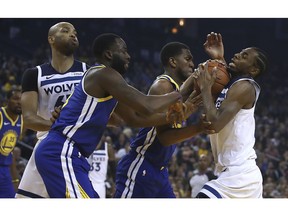 Minnesota Timberwolve's Andrew Wiggins, right, drives the ball against Golden State Warriors' Draymond Green, second from left, and Kevon Looney during the first half of an NBA basketball game Monday, Dec. 10, 2018, in Oakland, Calif. Minnesota's Taj Gibson, left, watches the play.