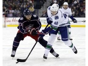 Vancouver Canucks forward Elias Pettersson, right, of Sweden, passes against Columbus Blue Jackets forward Josh Anderson during the first period of an NHL hockey game in Columbus, Ohio, Tuesday, Dec. 11, 2018.