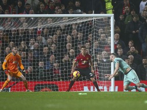 Arsenal's Shkodran Mustafi, right, heads the ball to score his side's first goal passing Manchester United's goalkeeper David de Gea, left, during the English Premier League soccer match between Manchester United and Arsenal at Old Trafford stadium in Manchester, England, Wednesday Dec. 5, 2018.