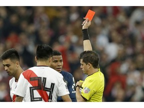 Referee Andres Cunha, of Uruguay, shows a red card to Wilmar Barrios of Argentina's Boca Juniors, center in blue, during a Copa Libertadores final soccer match between River Plate and Boca Juniors at the Santiago Bernabeu stadium in Madrid, Spain, Sunday, Dec. 9, 2018.