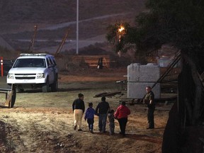 Migrants traveling with children walk up a hill to a waiting U.S. Border Patrol agent just inside San Ysidro, Calif., after climbing over the border wall from Playas de Tijuana, Mexico, Monday, Dec. 3, 2018. Thousands of Central American migrants who traveled with recent caravans want to seek asylum in the United States but face a decision between crossing illegally or waiting months, because the U.S. government only processes a limited number of those cases a day at the San Ysidro border crossing.