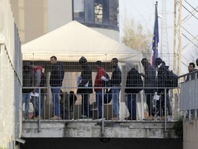 In this photo taken on  Friday, Dec. 7, 2018, people queue at the political asylum migration office at the Italian police headquarters, in Rome. Thousands of migrants in Italy are anxiously waiting to see if they will lose their housing and benefits following approval of a government-backed law that aims to reduce the number of migrants granted humanitarian protections.