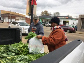 Zachary Osborne, left, buys mustard greens from Elaine Blair in Canton, Miss., on Friday, Dec. 7, 2018. Osborne and Blair each said people in Canton have been talking about voter fraud charges brought against seven people in connection to the 2017 Canton city elections. Six people were arrested Thursday, Dec. 6, 2018, and one Friday, Dec. 7.