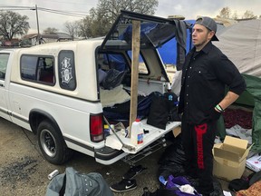 In this Tuesday, Dec. 4, 2018 photo Michael Jones organizes a pile of donated blankets, sleeping bags and clothes in a fairgrounds parking lot that's become home to some of the people displaced by California's deadliest wildfire in Chico, Calif. Jones lost nearly everything he owns when the fire destroyed his trailer and his mom's home in Paradise last month, but he's determined to stay put because he doesn't want to be a burden on his friends and relatives.