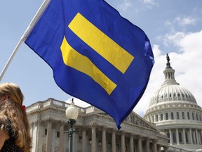 In this July 26, 2017 file photo, a supporter of LGBT rights holds up an "equality flag" on Capitol Hill in Washington, during an event held by Rep. Joe Kennedy, D-Mass. in support of transgender members of the military.