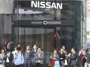 In this Dec. 4, 2018, photo, people stand in front of a showroom of Nissan in Tokyo. The company has ousted Carlos Ghosn as chairman, and a replacement has not yet been picked.