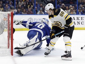 Tampa Bay Lightning goaltender Louis Domingue (70) makes a pad save on a shot by Boston Bruins right wing David Pastrnak (88) during the first period of an NHL hockey game Thursday, Dec. 6, 2018, in Tampa, Fla.