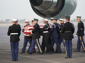 The flag-draped casket of former President George H.W. Bush is carried by a joint services military honor guard Wednesday, Dec. 5, 2018, at Ellington Field in Houston.