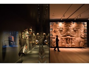 First Nations masks are displayed behind glass as a man walks past "The Dance Screen (The Scream Too)" - a red cedar panel by Haida master carver James Hart, at the Audain Art Museum in Whistler, B.C., on Sunday December 2, 2018. Nestled into a crop of towering trees in one of Canada's most popular skiing locales lies an astonishing collection of British Columbian art. The picturesque village of Whistler is better known for its mountains and resorts than galleries, but the museum offers visitors a respite from the slopes and an opportunity to take in work by a variety of artists.