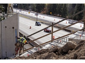 In this photo taken Oct. 4, 2018, a worker helps place tall panels on a wildlife bridge under construction as traffic on Interstate 90 passes below on Snoqualmie Pass, Wash. The stretch of highway crossing the Cascade Mountains cuts through old growth forest and wetlands, creating a dangerous border for wildlife everything from an elk down to a small salamander. The new crossing gives animals in these mountains a safer option for crossing the road: They'll be able to go above it.