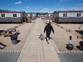 A Fort McMurray wildfire evacuee walks a dog at an oilfield work camp where approximately 500 evacuees were staying in Wandering River, Alta., on May 8, 2016.