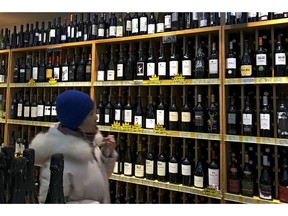 A woman walks by a shelve displaying bottles of American wine for sale at a supermarket in Beijing, Tuesday, Dec. 11, 2018. China's economy czar and the U.S. Treasury secretary discussed plans for talks on a tariff battle, the government said Tuesday, indicating negotiations are going ahead despite tension over the arrest of a Chinese tech executive.