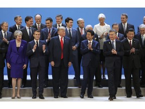 World leaders gather for a group photo at the start of the G20 Leader's Summit at the Costa Salguero Center in Buenos Aires, Argentina, Friday, Nov. 30, 2018. Bottom row from left are Britain's Prime Minister Theresa May, France's President Emmanuel Macron, President Donald Trump, Japan's Prime Minister Shinzo Abe, Argentina's President Mauricio Macri and China's President Xi Jinping. Behind are European Council's President Donald Tusk, the Netherlands' Prime Minister Mark Rutte, unidentified, Spain's Prime Minister Pedro Sanchez, unidentified, Canada's Prime Minister Justin Trudeau, unidentified, International Monetary Fund Managing Director Christine Lagarde, South Korea's President Moon Jae-in, unidentified, and Chile's President Sebastian Pinera.