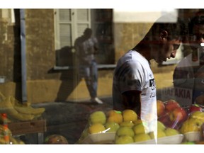 In this Tuesday, Nov. 20, 2018, migrants reflected on a window of a market at a neighborhood in central city of Nicosia, Cyprus. Migrant arrivals are down overall in Europe as some countries tighten their borders, but migrant trafficking networks seem to have set their sights on Cyprus.