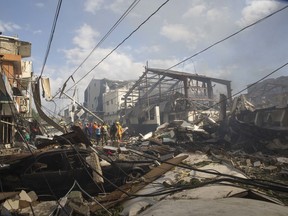 Search and rescue stand in the debris caused by an explosion at the Polyplas plant in the Villas Agricolas neighborhood in Santo Domingo, Dominican Republic, Wednesday, Dec. 5, 2018. The mayor told reporters the fire began when a boiler exploded early Wednesday afternoon at the plastics company. Authorities say at least two people have died.