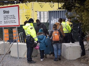 A family is arrested by RCMP officers as they cross the border into Canada from the United States as asylum seekers on Wednesday, April 18, 2018 near Champlain, NY.