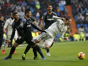 Real Madrid's Luka Modric, right, is tackled by Sevilla's Sergio Escudero during La Liga soccer match between Real Madrid and Sevilla at the Bernabeu stadium in Madrid, Spain, Saturday, Jan. 19, 2019.