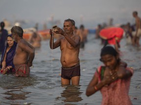 An Indian Hindu pilgrim prays at Sangam, the confluence of the rivers Ganges, Yamuna and mythical Saraswati, during the Kumbh Mela festival in Allahabad, India, Monday, January 14, 2019. Millions of Hindu pilgrims are expected to take part in the large religious congregation.