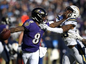 Baltimore Ravens quarterback Lamar Jackson (8) tries to break free from Los Angeles Chargers free safety Derwin James in the first half of an NFL wild card playoff football game, Sunday, Jan. 6, 2019, in Baltimore.