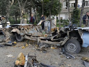 In this photo released by the Syrian official news agency SANA, people gather at the site of an explosion in the Adawi neighborhood of Damascus, Syria, Thursday, Jan. 24, 2019. Syrian state media reported that the bomb caused property damage but no casualties. The Russian Embassy is located several hundred meters (yards) away. (SANA via AP)