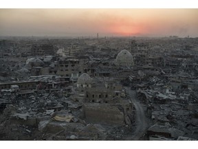 FILE - In this July 11, 2017 file photo, the sun sets behind destroyed buildings in the west side of Mosul, Iraq. For centuries, residents of Mosul have spoken a unique form of Arabic enriched by the Iraqi city's long history as a crossroads of civilization, a singsong dialect that many now fear will die out after years of war and displacement. Much of Mosul's Old City, where speakers of the dialect are concentrated, was completely destroyed in the war against the Islamic State group.