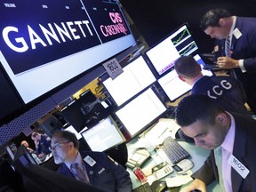 FILE - In this Aug. 5, 2014, file photo, specialist Michael Cacace, foreground right, works at the post that handles Gannett on the floor of the New York Stock Exchange. The Wall Street Journal is reporting that MNG Enterprises, better known as Digital First Media, is preparing to bid for newspaper publisher Gannett Co.