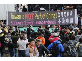 FILE - In this Jan. 16, 2016, file photo, pro-independence supporters carry a banner shouting that Taiwan is not part of China outside the Democratic Progressive Party presidential campaign headquarters in Taipei, Taiwan. The residents of this self-governing island are supporting their president Tsai Ing-wen as she stands up to China's calls for unification with the mainland.