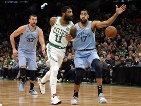 Boston Celtics' Kyrie Irving throws a behind-the-back pass past Memphis Grizzlies' Garrett Temple (17) during the first quarter of an NBA basketball game Friday, Jan. 18, 2019, in Boston.