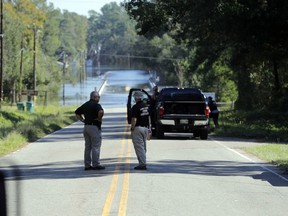 FILE - In this Wednesday, Sept. 19, 2018, file photo, responders congregate near where two people drowned the evening before when they were trapped in a Horry County Sheriff's transport van while crossing an overtopped bridge over the Little Pee Dee River on Highway 76, during rising floodwaters in the aftermath of Hurricane Florence in Marion County, S.C. Charges are expected to be filed Friday, Jan. 4, 2019, against two South Carolina law enforcement officers who were transporting two mental patients who drowned while locked in the back of a van during the hurricane.