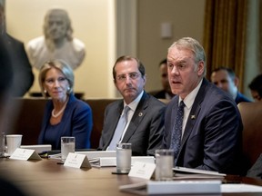 FILE - In this Thursday, Aug. 16, 2018 file photo, Interior Secretary Ryan Zinke, right, accompanied by Education Secretary Betsy DeVos, left, and Health and Human Services Secretary Alex Azar, center, speaks during a cabinet meeting in the Cabinet Room of the White House, in Washington. As former U.S. Interior Secretary Zinke exits Washington amid a cloud of unresolved ethics investigations, he says he has lived up to the conservation ideals of Teddy Roosevelt and insists the myriad allegations against him will be proven untrue.