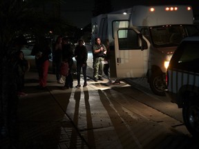 In this Dec. 11, 2018, photo an official counts asylum-seekers as they are dropped off from an immigration detention center to a shelter in San Diego. Since late October 2016, the U.S. has been releasing asylum-seeking families with little time to arrange travel, which it blames on lack of detention space. To avoid putting penniless families on the streets, charities and advocacy groups from California to Texas are scrambling to provide shelter, food, clothes and help buying bus and plane tickets.