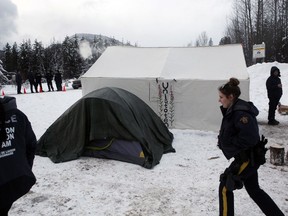 RCMP members gather at a Wet'suwet'en checkpoint after representatives from Coastal GasLink and contractors make their way through an exclusion zone at the 27 kilometre marker towards the Unist'ot'en camp to remove barriers on a bridge over the Morice River, southwest of Houston, B.C., on Friday, January 11, 2019.