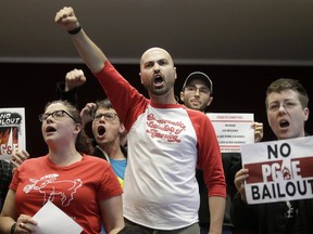 Brandon Harami, center, and others yell during a California Public Utilities Commission meeting in San Francisco, Monday, Jan. 28, 2019. California regulators have approved a measure allowing Pacific Gas & Electric Corp. to immediately obtain credit and loans while the company is under Chapter 11 bankruptcy protection.