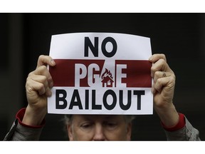 A man holds up a sign at a rally before a California Public Utilities Commission meeting in San Francisco, Monday, Jan. 28, 2019. California regulators have approved a measure allowing Pacific Gas & Electric Corp. to immediately obtain credit and loans while the company is under Chapter 11 bankruptcy protection.