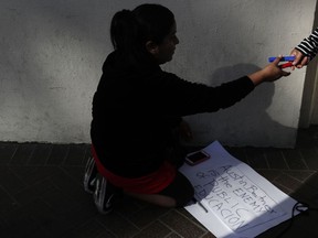 Noemi De La Cruze, whose three children are attending Los Angeles Unified School District schools, makes signs before a news conference outside the LAUSD headquarters Wednesday, Jan. 9, 2019, in Los Angeles, Calif. The union representing teachers in Los Angeles has postponed the start of a possible strike until Monday because of uncertainty over whether a judge would order a delay.