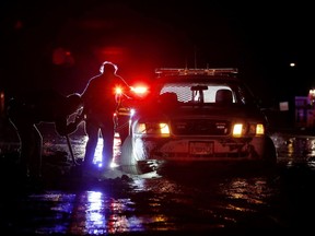 In this Saturday, Jan 5, 2019, photo sheriff's deputies work to free their patrol cruiser from mud covering a stretch of Pacific Coast Highway in Malibu, Calif. A winter storm unleashed mudslides in Southern California wildfire burn areas and trapped motorists on a major highway, and the northern part of the state is bracing for more wet weather. Saturday's deluge loosened hillsides in Malibu where a major fire burned last year, clogging the Pacific Coast Highway with mud and debris.