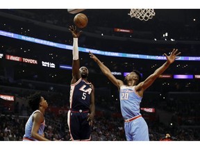 Los Angeles Clippers' Montrezl Harrell (5) shoots between Sacramento Kings' De'Aaron Fox, left, and Harry Giles (20) during the first half of an NBA basketball game Sunday, Jan. 27, 2019, in Los Angeles.