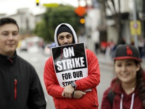 Artan Gasparians, center, a physical education teacher with Fulton College Preparatory in Van Nuys, Calif., holds a sign as he marches during a rally Tuesday, Jan. 15, 2019, in Los Angeles. Teachers in the huge Los Angeles Unified School District walked picket lines again Tuesday as administrators urged them to return to classrooms and for their union to return to the bargaining table.