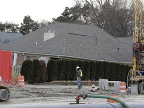 FILE - In this Jan. 4, 2017 file photo, a construction worker walks by a home collapsed by a sinkhole in Fraser, Mich. Officials said Wednesday, Jan. 9, 2019, that the sinkhole north of Detroit that damaged homes and cost $75 million to fix was caused by human error that allowed the quick release of waste and water into a sewer line. The pipe collapsed and caused the Dec. 24, 2016, sinkhole which grew to football field-size.