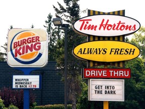 Burger King and Tim Hortons signs are displayed on St. Laurent Boulevard in Ottawa on Monday, August 25, 2014. Restaurant Brands International Inc. raised its dividend as it announced changes in its executive suite.