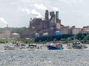 Fishing boats pass the Northern Pulp mill as concerned residents, fishermen and Indigenous groups protest the mill's plan to dump millions of litres of effluent daily into the Northumberland Strait in Pictou, N.S., on July 6, 2018. A First Nation in northern Nova Scotia is taking a novel approach to ensuring that a highly polluted waste water treatment facility on its land is shut down just over a year from now. Under legislation passed in 2015, the provincial government has committed to closing the Boat Harbour facility by Jan. 31, 2020 -- exactly one year from this Thursday -- and the Pictou Landing First Nation plans to mark the beginning of an official countdown on that day.