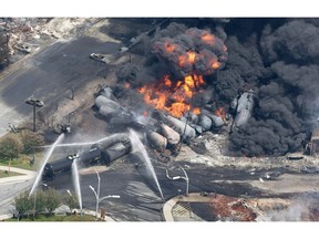 Smoke rises from railway cars that were carrying crude oil after derailing in downtown Lac-Megantic, Que., Saturday, July 6, 2013. Canadian members of Parliament have passed a unanimous motion condemning Netflix for using images of the Lac-Megantic rail disaster in fictional dramas and are demanding financial compensation for the Quebec community for using the tragic images without consent.THE CANADIAN PRESS/Paul Chiasson