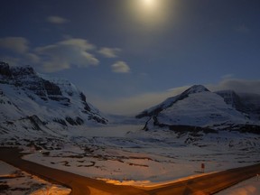 The Athabasca Glacier, centre, part of the Columbia Icefields in Jasper National Park, Alta., is seen in moonlight on May 7, 2014. Parks Canada says it won't go ahead with a controversial plan to build a bike trail along the scenic Icefields Parkway between Banff and Jasper National Parks. The agency had budgeted about $66 million to build the 107-kilometre route, along with other facilities such as parking lots, campsites and washrooms. It says that money will now be spent elsewhere in the national park system.