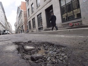 A pothole is seen on St. Paul street Friday, March 18, 2016 in Montreal. Municipal and provincial governments in Canada are all looking for better ways to deal with their growing pothole problems, but none are properly tracking whether the repairs they do now are effective over time, says the author of a soon-to-be completed study on the roadway menaces.
