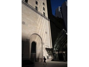 A woman walks through Toronto's financial district on July 30, 2018. A new report looking at the country's highest-paid CEOs is adding new evidence to the argument that women face a "double-pane glass ceiling" at the top of Canada's corporate ladder -- first in getting in the executive suite and, once there, earning as much as their male counterparts. The Canadian Centre for Policy Alternatives calculates that of the more than 1,200 named executive officers, or NEOs -- defined by regulators as a company's most highly compensated roles -- at 249 publicly traded companies in Canada, women earn about 68 cents for every dollar earned by their male counterparts.