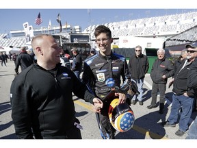 Jordan Taylor, center, makes his way to the garages after a practice session for the IMSA 24 hour race at Daytona International Speedway, Friday, Jan. 25, 2019, in Daytona Beach, Fla.